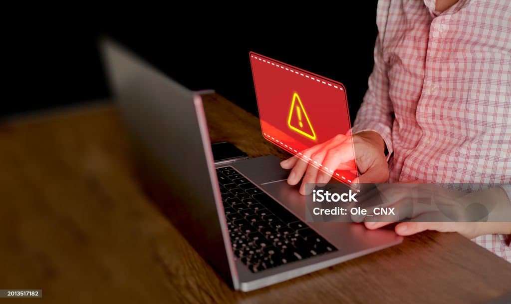 Cyber security concept. Red system hacked warning sign alerts on a computer notebook screen. Cybercrime, virus, online hacking, cyber attack, malicious malware or software. Artificial Intelligence Stock Photo