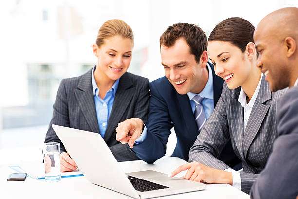Business Colleagues Working On Laptop Businessman pointing at laptop screen while sitting amidst multi-ethnic colleagues. Horizontal shot. Executors And Administrators stock pictures, royalty-free photos & images